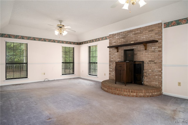 unfurnished living room with carpet flooring, a textured ceiling, a wood stove, and ceiling fan