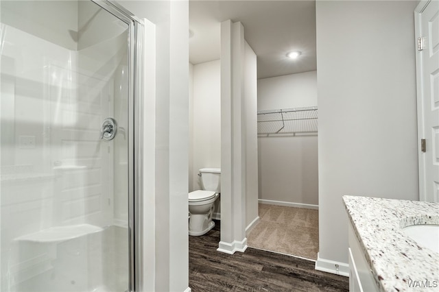 bathroom with wood-type flooring, vanity, toilet, and an enclosed shower