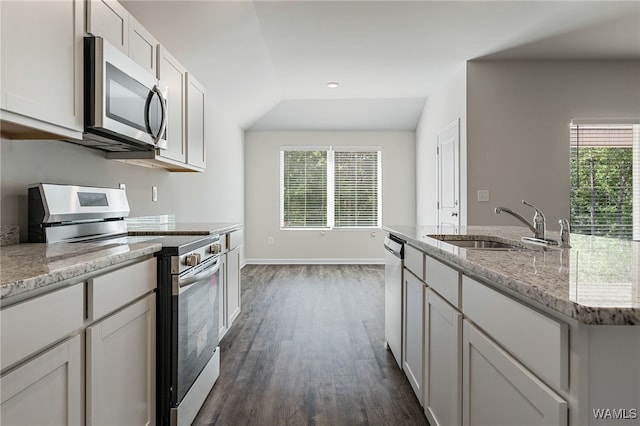 kitchen featuring light stone countertops, sink, dark wood-type flooring, lofted ceiling, and appliances with stainless steel finishes