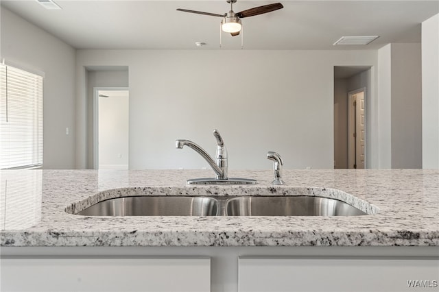 kitchen featuring light stone counters and sink