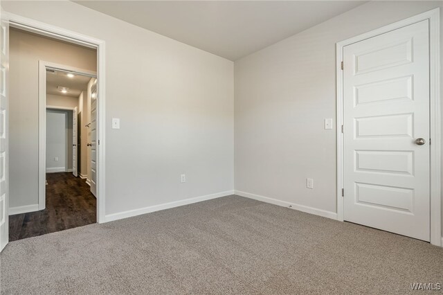 unfurnished room featuring dark colored carpet