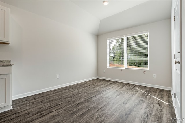 unfurnished room featuring dark hardwood / wood-style floors and vaulted ceiling