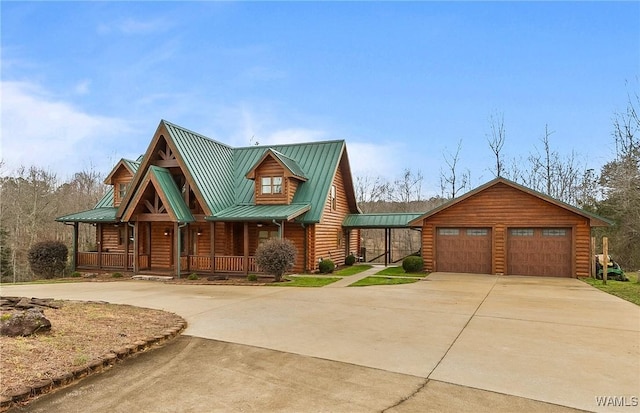 log cabin featuring a detached garage, an outbuilding, covered porch, and metal roof