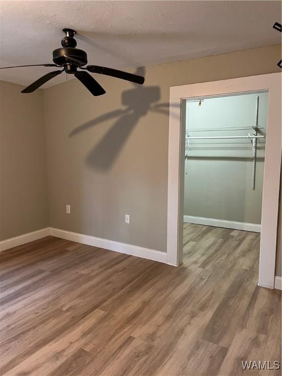 unfurnished bedroom with ceiling fan, wood-type flooring, and a textured ceiling