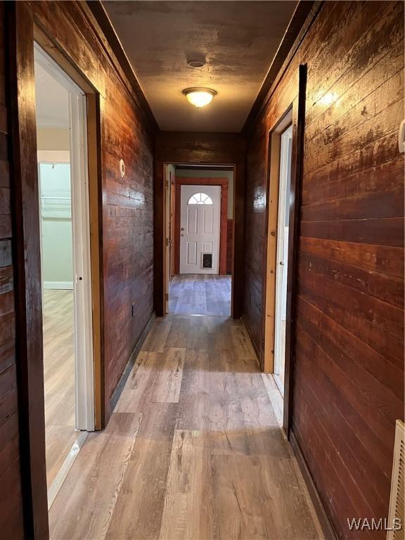 hallway featuring light wood-type flooring and wood walls