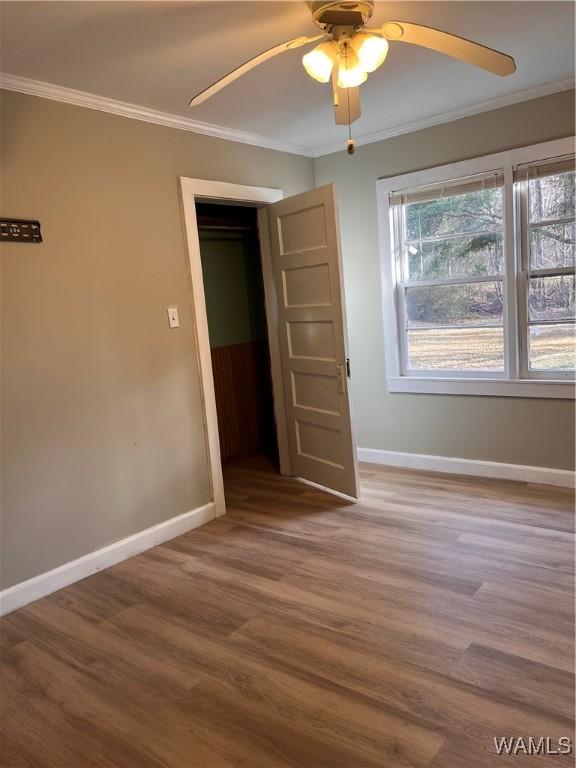 empty room with crown molding, ceiling fan, and hardwood / wood-style flooring