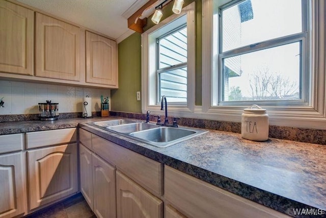 kitchen with sink, decorative backsplash, dark tile patterned floors, and light brown cabinets