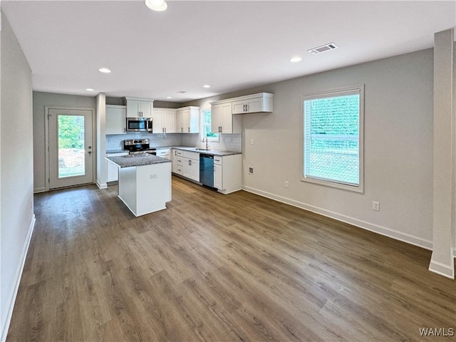 kitchen with visible vents, a kitchen island, baseboards, white cabinetry, and stainless steel appliances