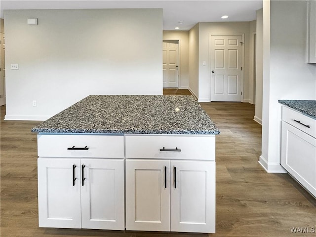 kitchen featuring dark stone counters, baseboards, dark wood finished floors, and white cabinetry