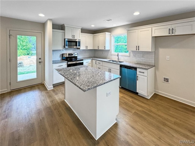kitchen with white cabinets, stainless steel appliances, light stone counters, and a sink
