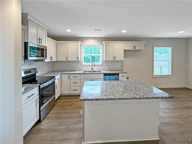 kitchen with stainless steel appliances, visible vents, a sink, and wood finished floors
