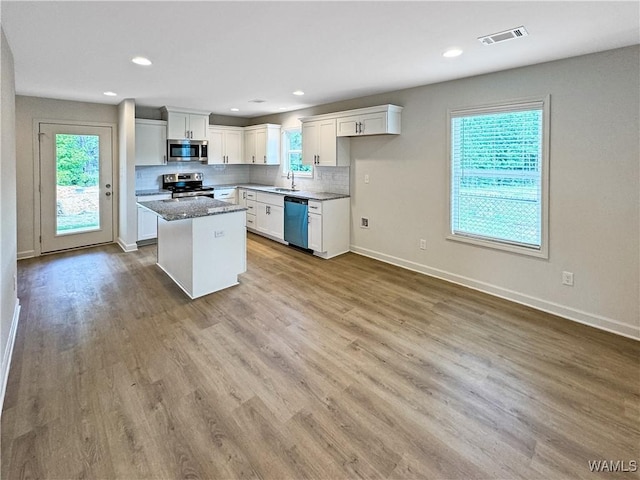 kitchen featuring visible vents, a center island, wood finished floors, white cabinets, and stainless steel appliances