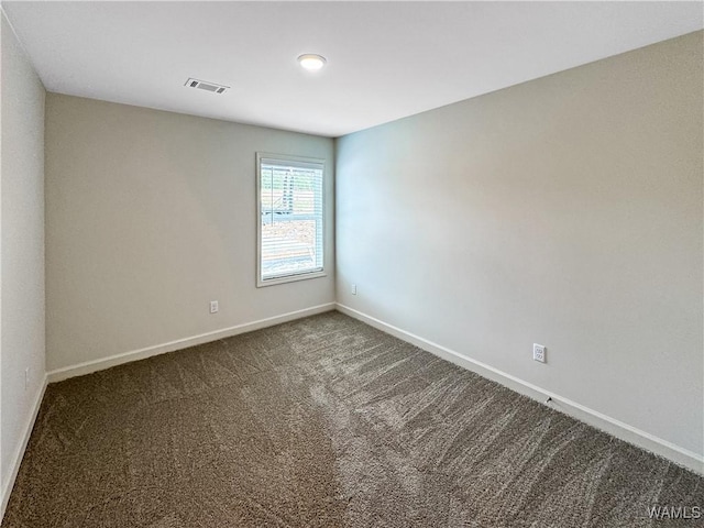 empty room with visible vents, baseboards, and dark colored carpet