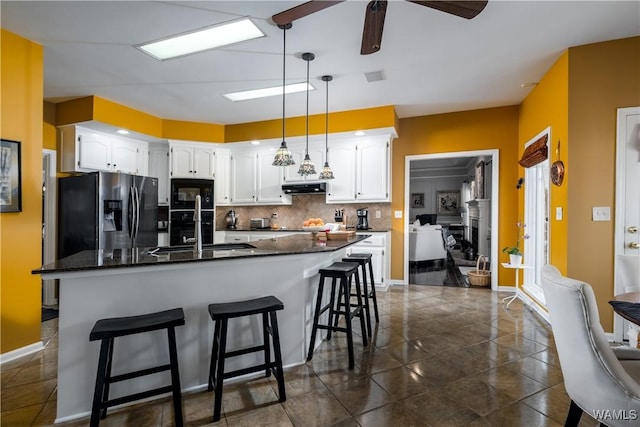 1137 Germantown Rd, Tuscaloosa, AL 35406 - kitchen featuring refrigerator with ice dispenser, black microwave, white cabinetry, decorative backsplash, and under cabinet range hood