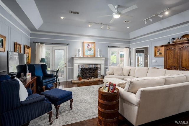 1137 Germantown Rd, Tuscaloosa, AL 35406 - living room featuring dark wood finished floors, rail lighting, ceiling fan, a brick fireplace, and a tray ceiling