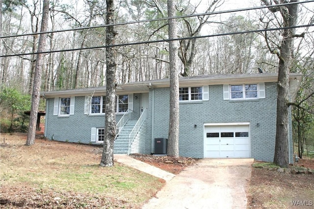 view of front of house with brick siding, central air condition unit, stairway, concrete driveway, and a garage