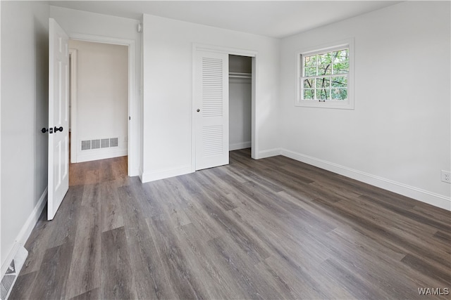 unfurnished bedroom with a closet and dark hardwood / wood-style flooring