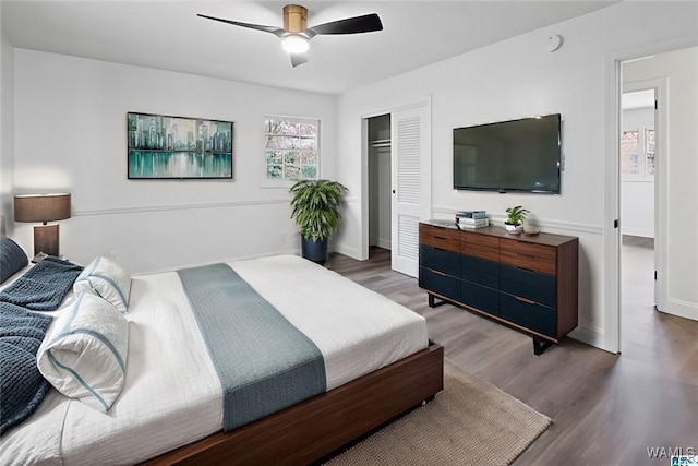 bedroom featuring baseboards, wood finished floors, a closet, and ceiling fan