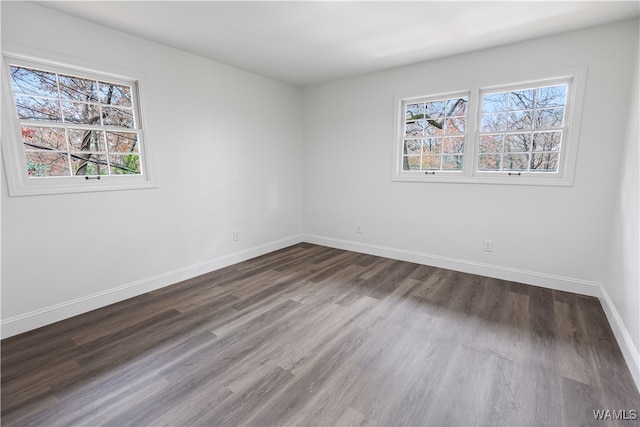 spare room with dark hardwood / wood-style flooring and a healthy amount of sunlight