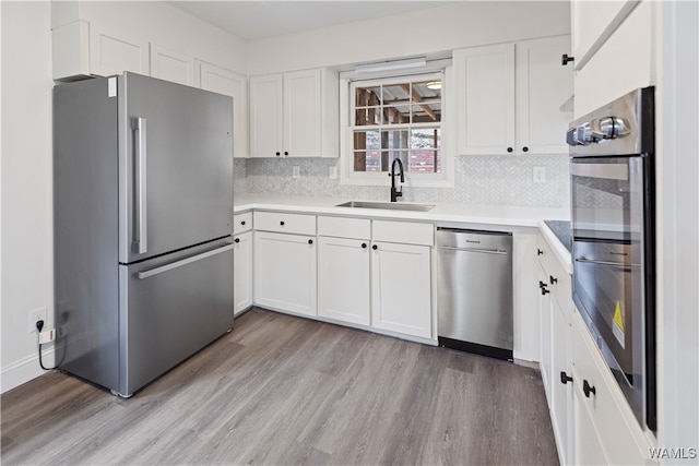 kitchen featuring light hardwood / wood-style flooring, stainless steel appliances, tasteful backsplash, white cabinetry, and sink