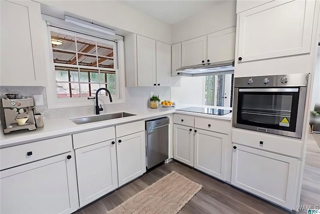 kitchen featuring appliances with stainless steel finishes, white cabinetry, light countertops, and a sink