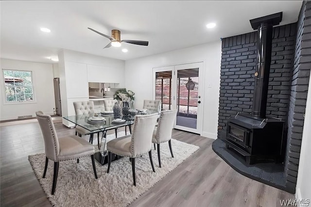 dining area featuring baseboards, ceiling fan, recessed lighting, a wood stove, and wood finished floors