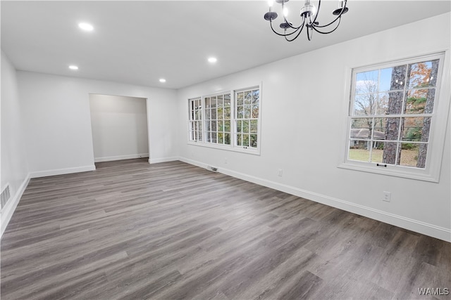 unfurnished room featuring an inviting chandelier and wood-type flooring