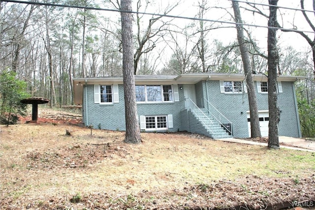 view of front of property with stairway, a garage, brick siding, and driveway