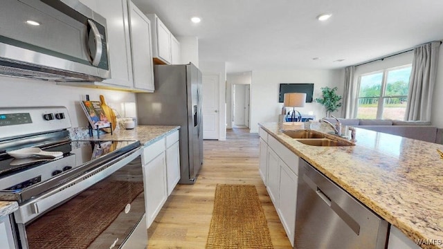 kitchen featuring white cabinets, light stone countertops, light wood-type flooring, and appliances with stainless steel finishes