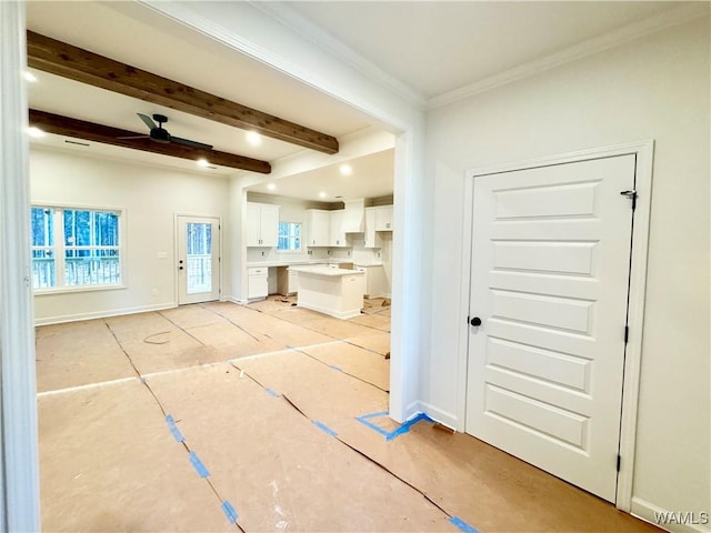 interior space featuring ornamental molding, beamed ceiling, baseboards, and a ceiling fan