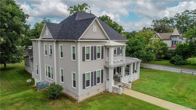 view of front of home with a balcony, a front lawn, and cooling unit