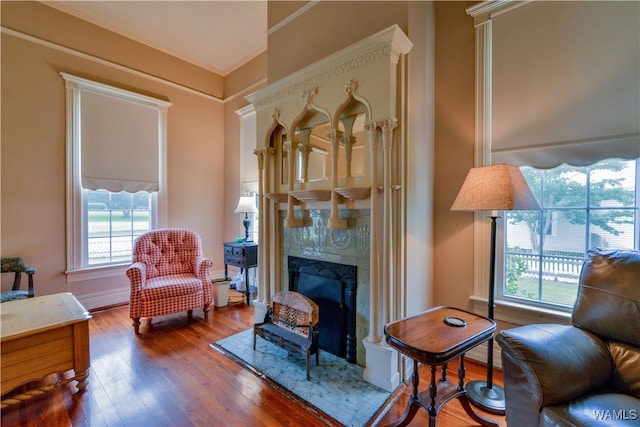 living area featuring hardwood / wood-style flooring, crown molding, and a high end fireplace