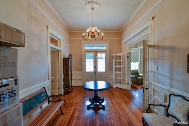 exercise area featuring a chandelier, french doors, ornamental molding, and hardwood / wood-style flooring