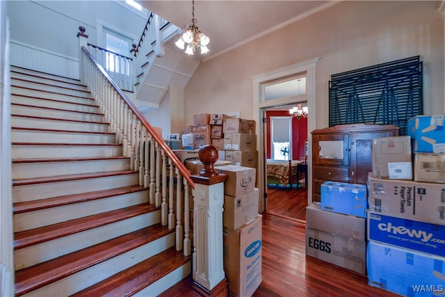 stairway with a chandelier, ornamental molding, hardwood / wood-style flooring, and lofted ceiling