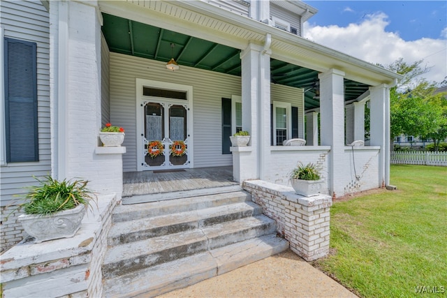 entrance to property featuring a porch and a lawn