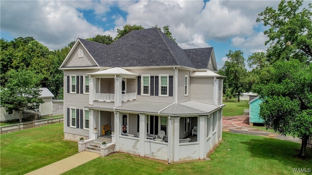 rear view of house with a porch, a yard, and a balcony