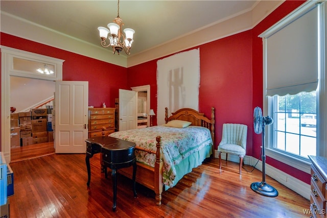 bedroom featuring hardwood / wood-style floors, a chandelier, and ornamental molding