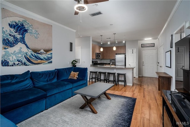 living room with ceiling fan, light wood-type flooring, sink, and ornamental molding