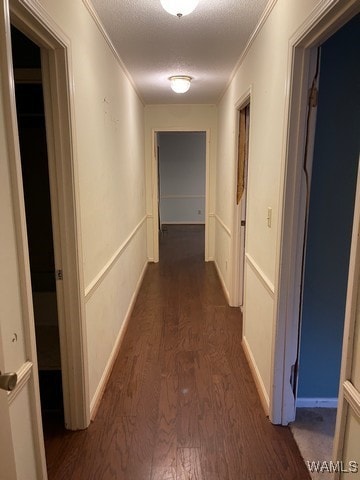 hall with a textured ceiling, dark hardwood / wood-style flooring, and crown molding