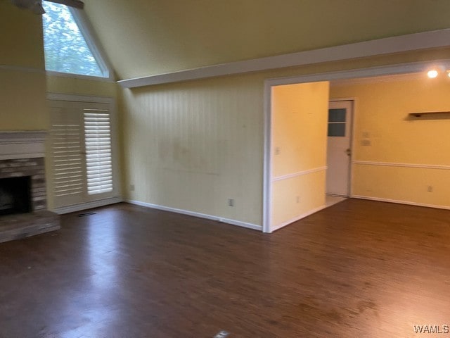 unfurnished living room with dark hardwood / wood-style flooring, a stone fireplace, and high vaulted ceiling