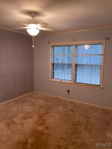 carpeted empty room with ceiling fan, crown molding, and a healthy amount of sunlight