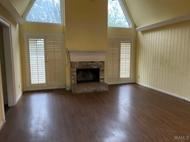 unfurnished living room featuring dark hardwood / wood-style floors, high vaulted ceiling, and a brick fireplace