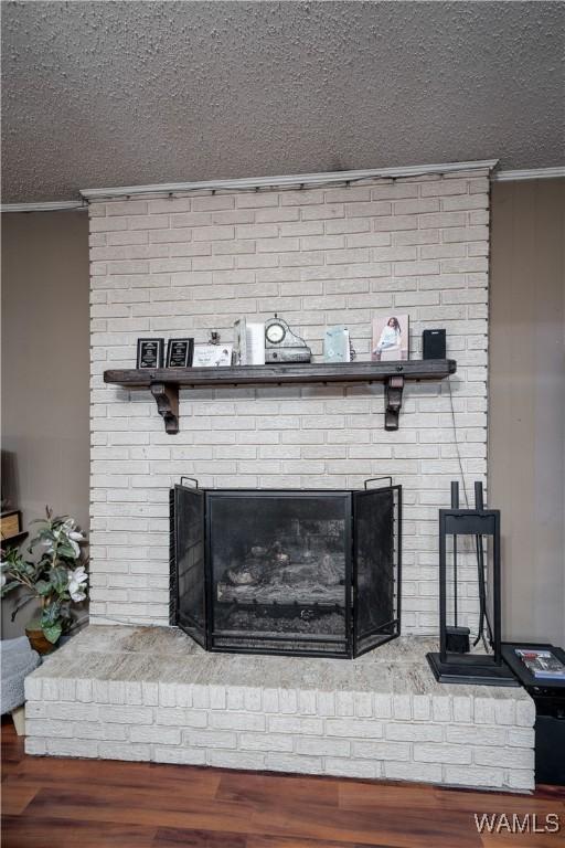 interior details with hardwood / wood-style floors, a textured ceiling, and a brick fireplace