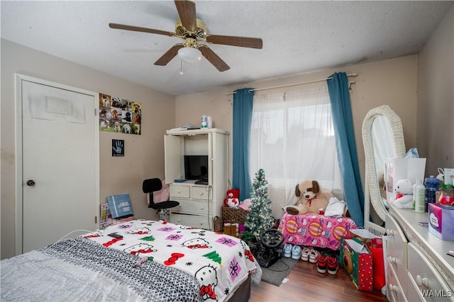 bedroom featuring hardwood / wood-style flooring, ceiling fan, and a textured ceiling