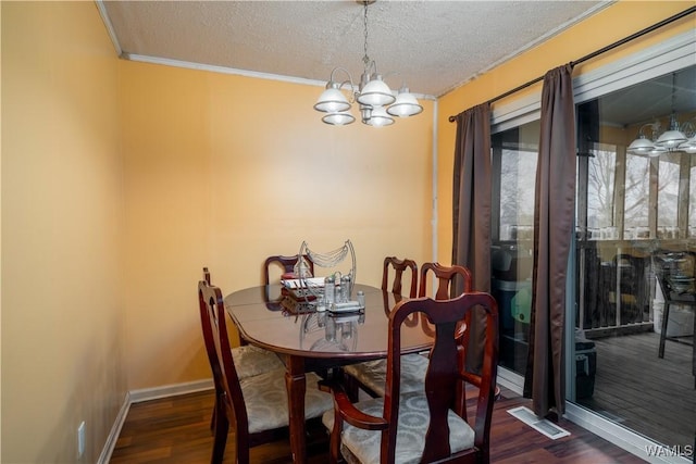 dining space with ornamental molding, a textured ceiling, dark hardwood / wood-style floors, and a notable chandelier