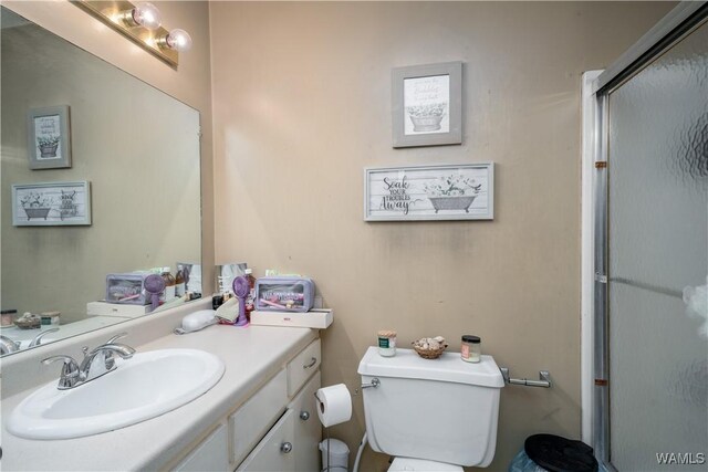 bathroom with toilet, an enclosed shower, and vanity