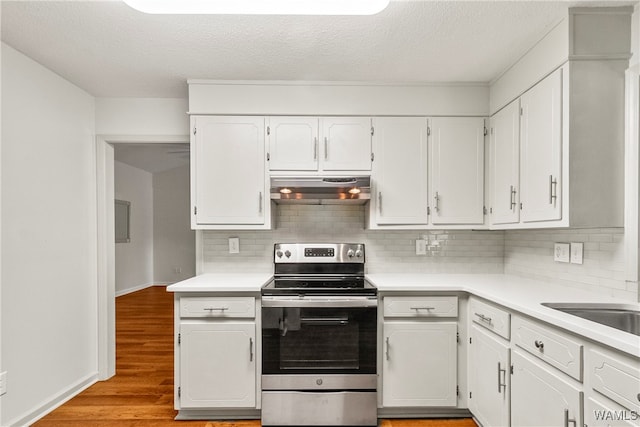 kitchen with tasteful backsplash, white cabinets, stainless steel range with electric cooktop, and light wood-type flooring