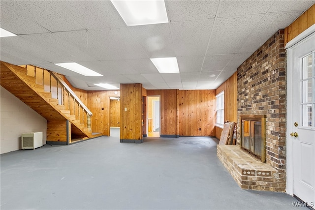 basement with a paneled ceiling, plenty of natural light, and a fireplace