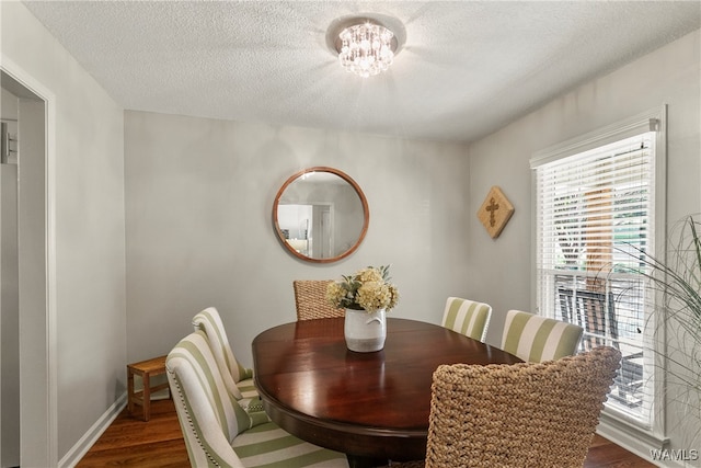 dining area featuring a chandelier, a textured ceiling, and dark wood-type flooring