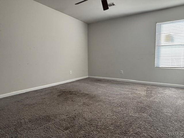 carpeted empty room featuring baseboards, visible vents, and ceiling fan